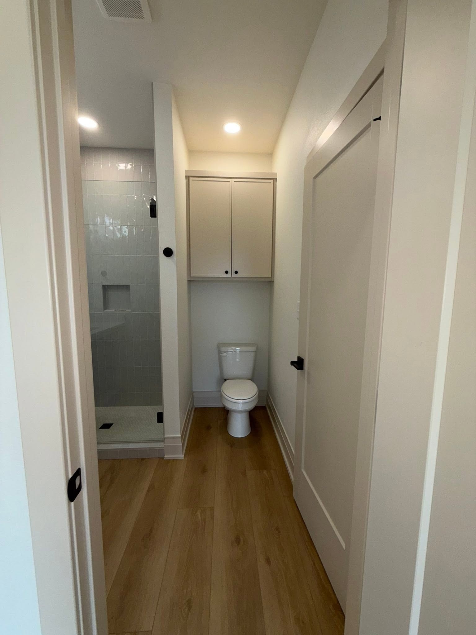 Final clean — guest bath with glass shower enclosure and wood floors